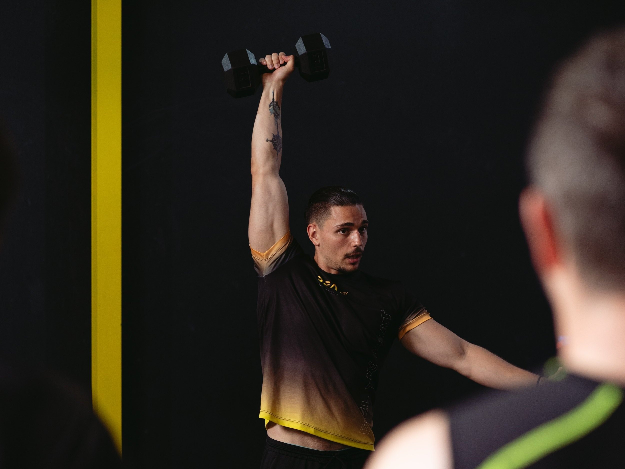 Entrenador guiando un ejercicio con mancuerna en Beat Training Club